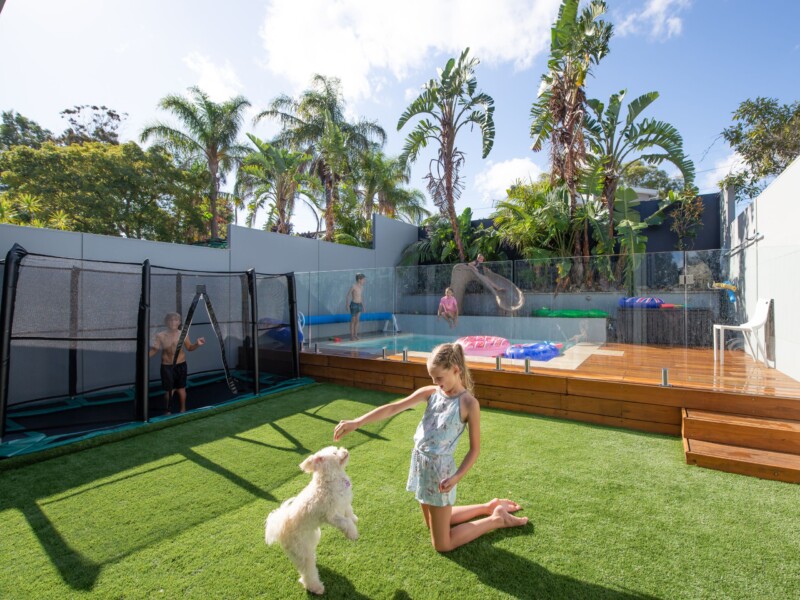 TrendWall dividing fence around duplex backyard featuring a trampoline and pool.