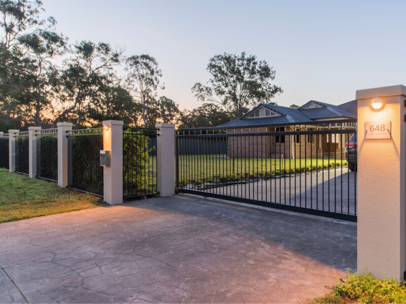 Grand front driveway and gate entrance with integrated lighting