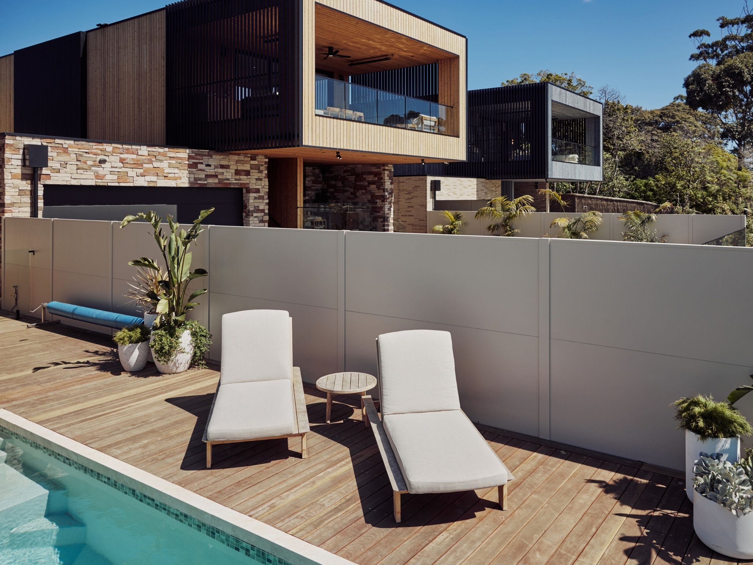 The pale TrendWall® boundary sits behind the loungers and planting, giving the pool area a sense of privacy without competing with the home’s layered materials. It helps the space feel complete, whether it is being used for an afternoon swim or a long lunch outdoors.