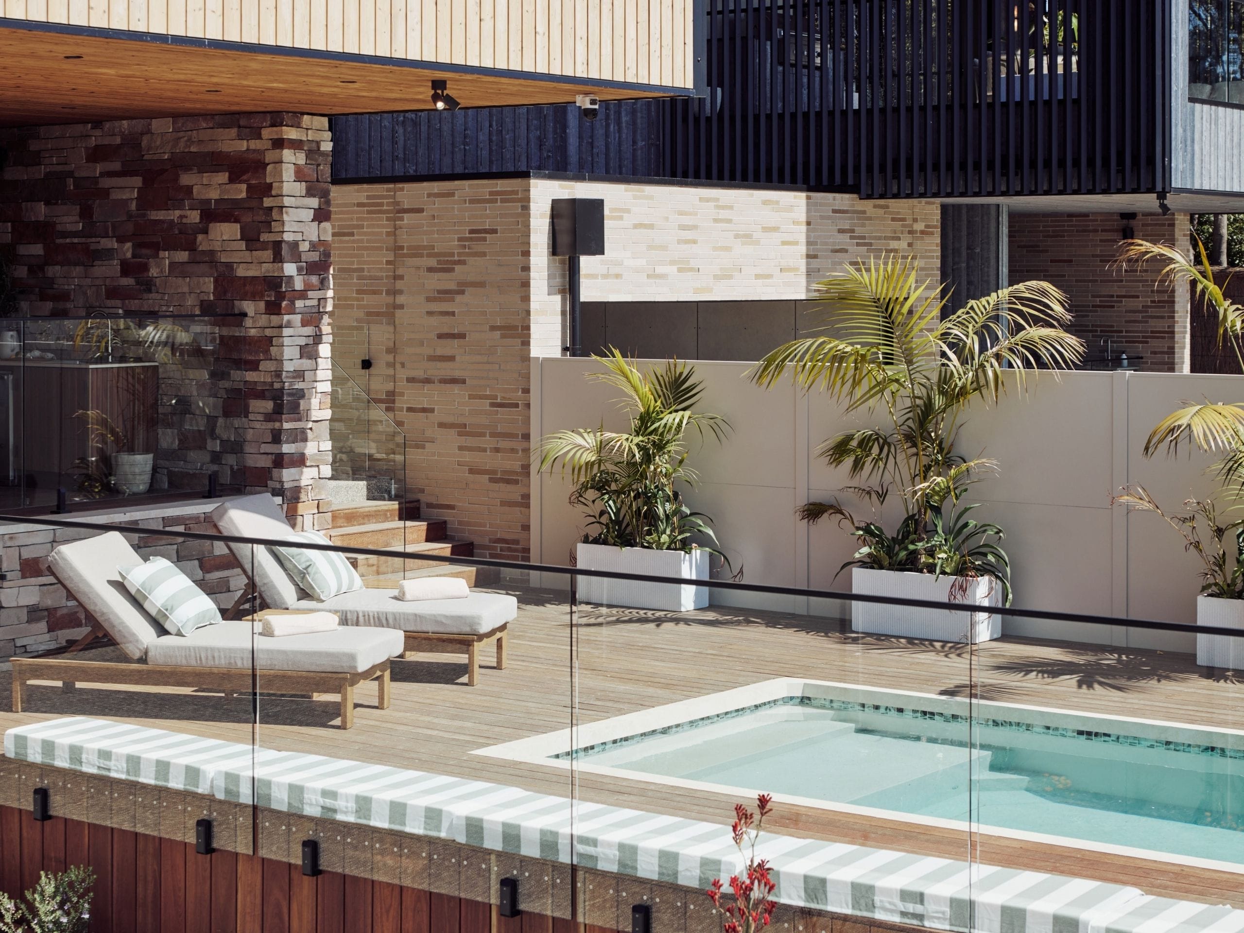 Adam and Jolene made entertaining the focus of House 1. A timber deck wraps around the pool, connecting sun loungers with an outdoor kitchen, barbecue and pizza oven. An island with bar stools gives guests a place to gather close to the water, while mosaic detailing adds a subtle finish to the pool.