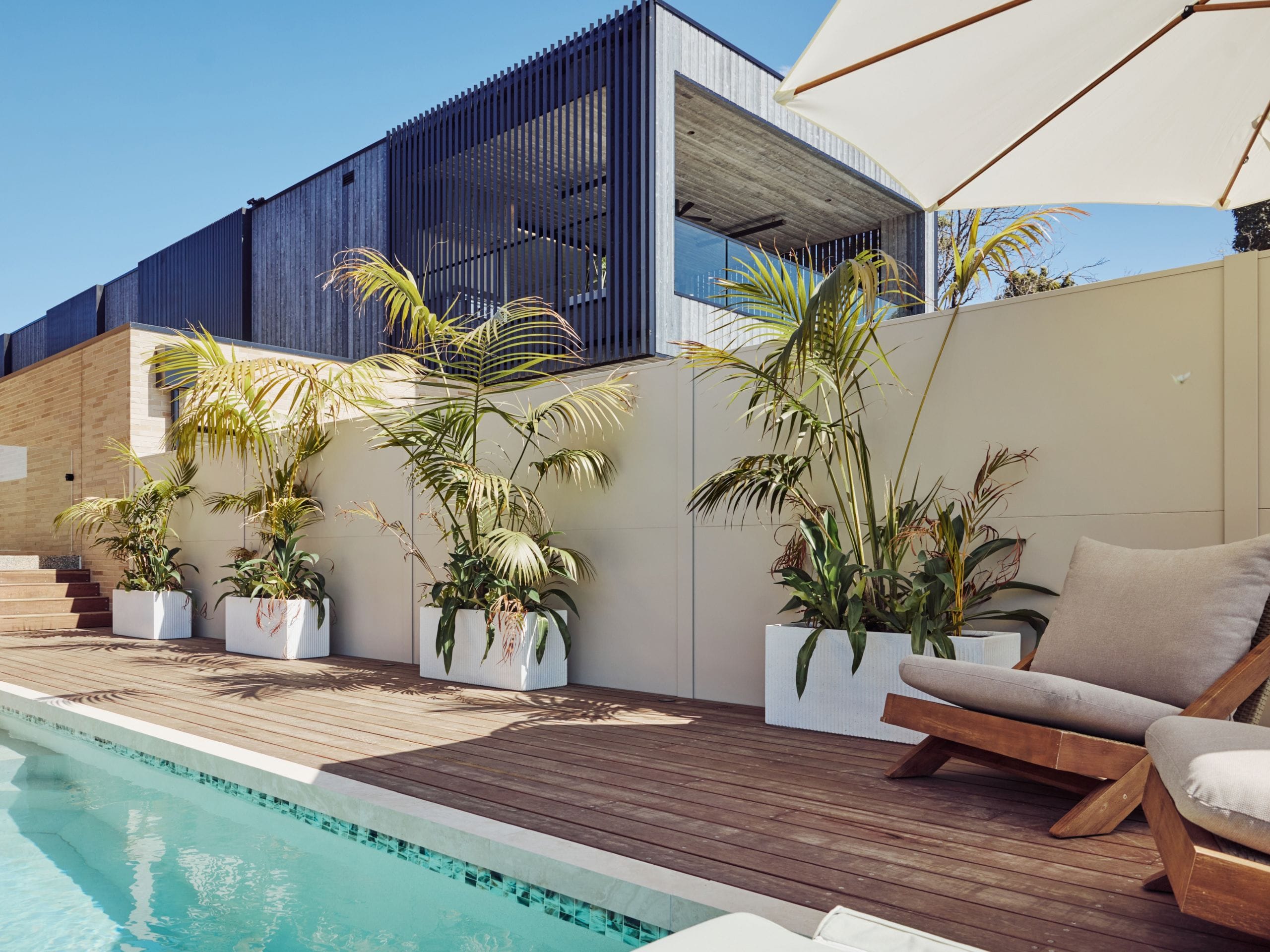 Loungers by the pool invite slower afternoons, while the covered dining area looks out towards the water.